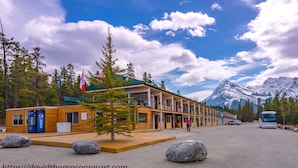 A log cabin-style building with a green roof and a mountain backdrop. - David Thompson Resort Hotel (Cline River)
