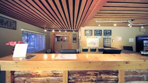 A reception desk with a wooden counter, a clock, and a sign that reads "Welcome". - David Thompson Resort Hotel (Cline River)
