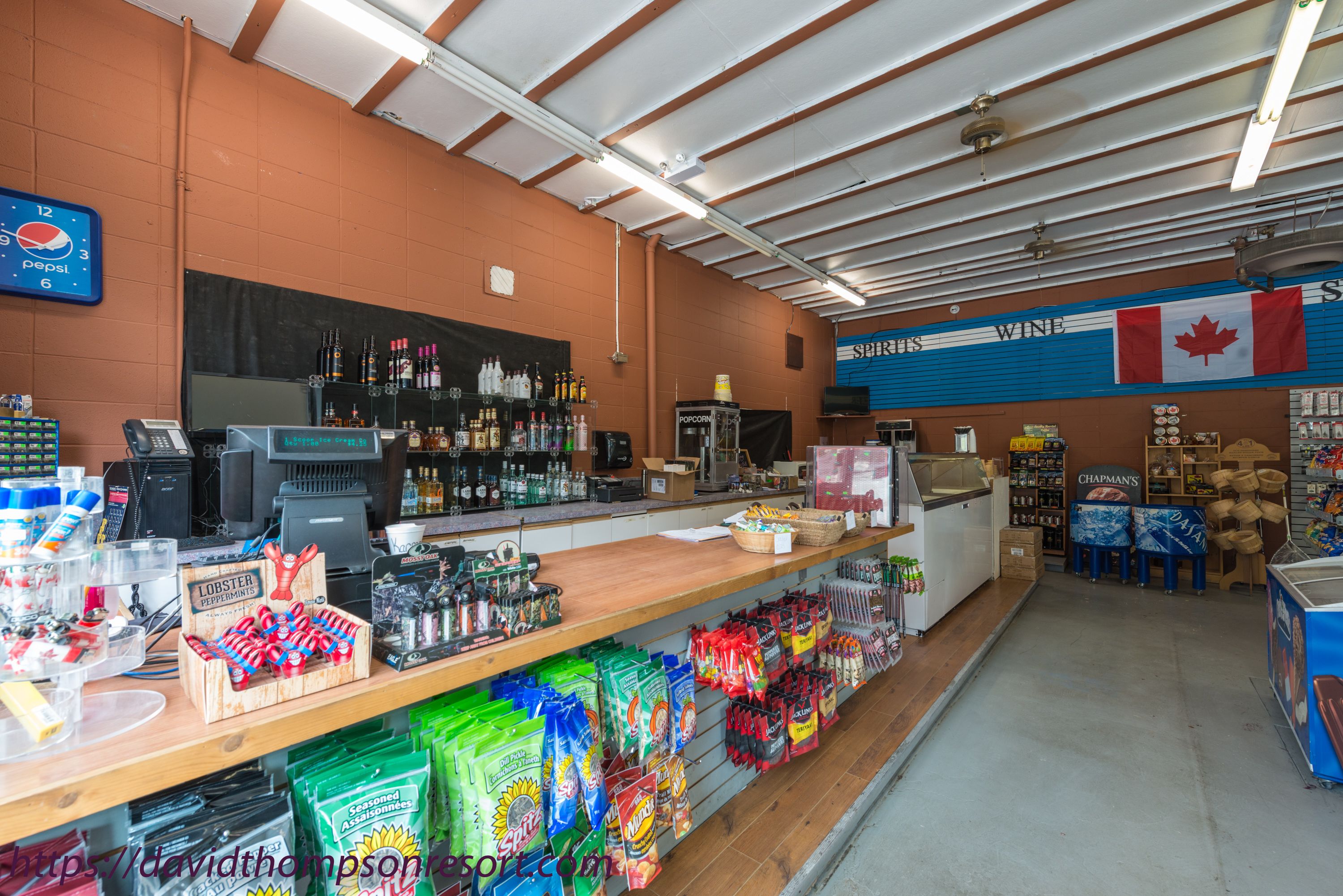 A store interior with a counter, shelves stocked with products, and a Canadian flag.