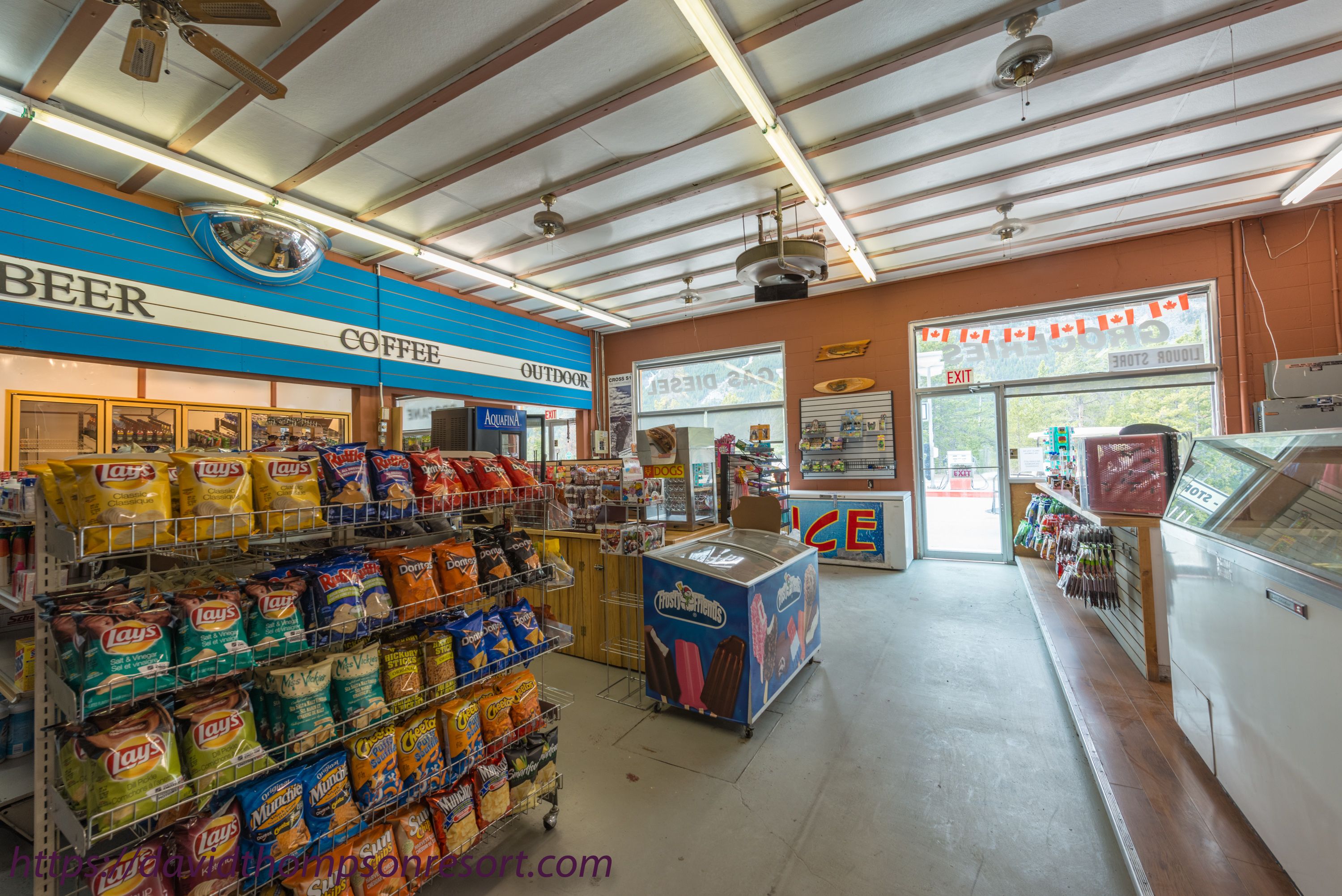 A grocery store interior with aisles of snacks, a coffee section, and an exit sign.