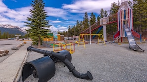 A playground with a slide, climbing structures, and a cannon. - David Thompson Resort Hotel (Cline River)