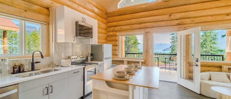 A log cabin with a kitchen, dining area, and a balcony with a view of the mountains.