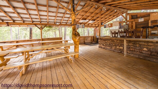 A covered outdoor area with wooden benches and a stone wall. - David Thompson Resort Hotel (Cline River)