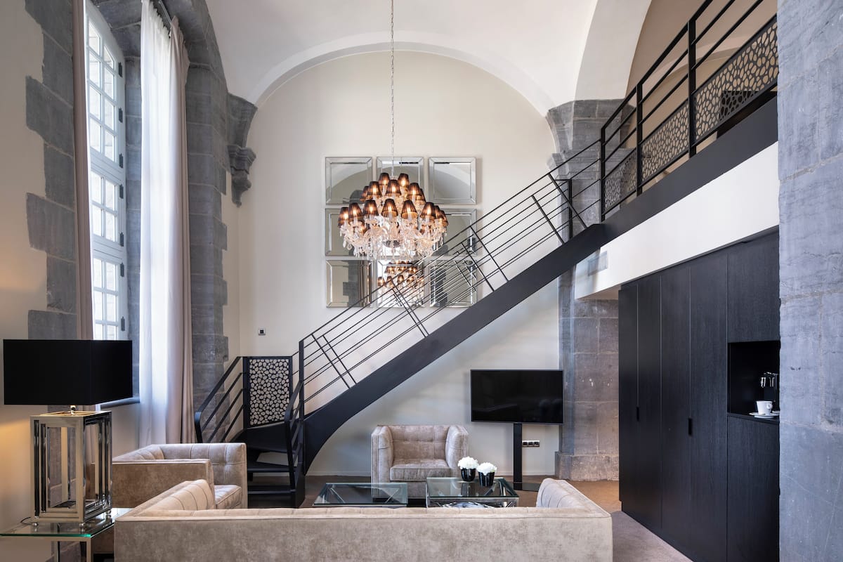 A spacious living area with a grand staircase, a chandelier, and modern furnishings.