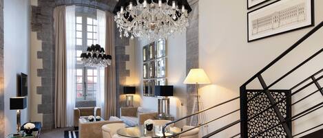 A modern living room with a chandelier, seating, and artwork on the walls.