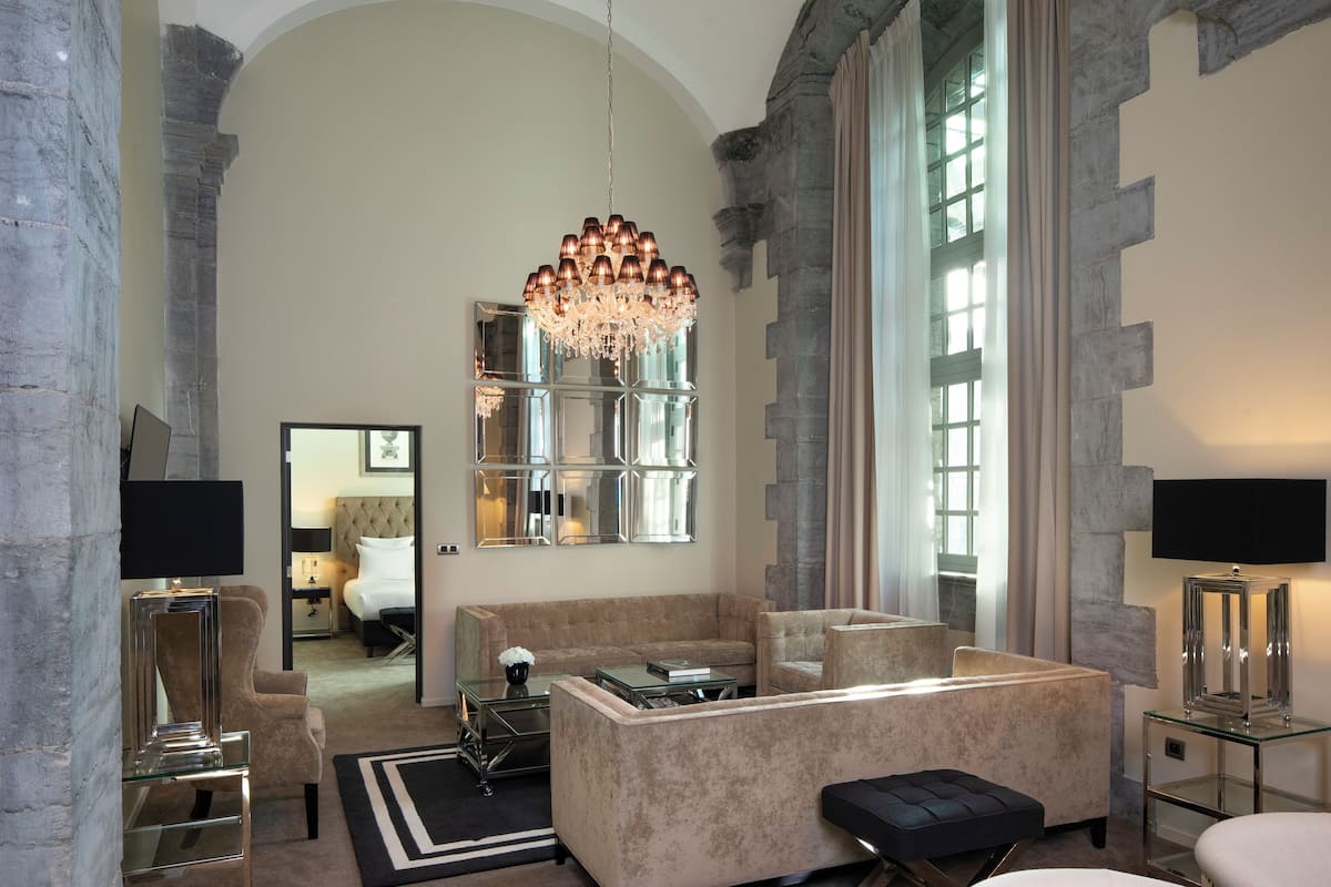 A spacious living area with a large chandelier, a sofa set, and a television on a stand.