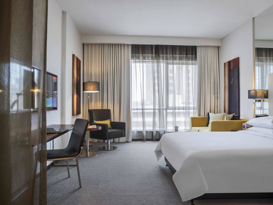 A hotel room with a large bed, two armchairs, a desk, and a lamp.
