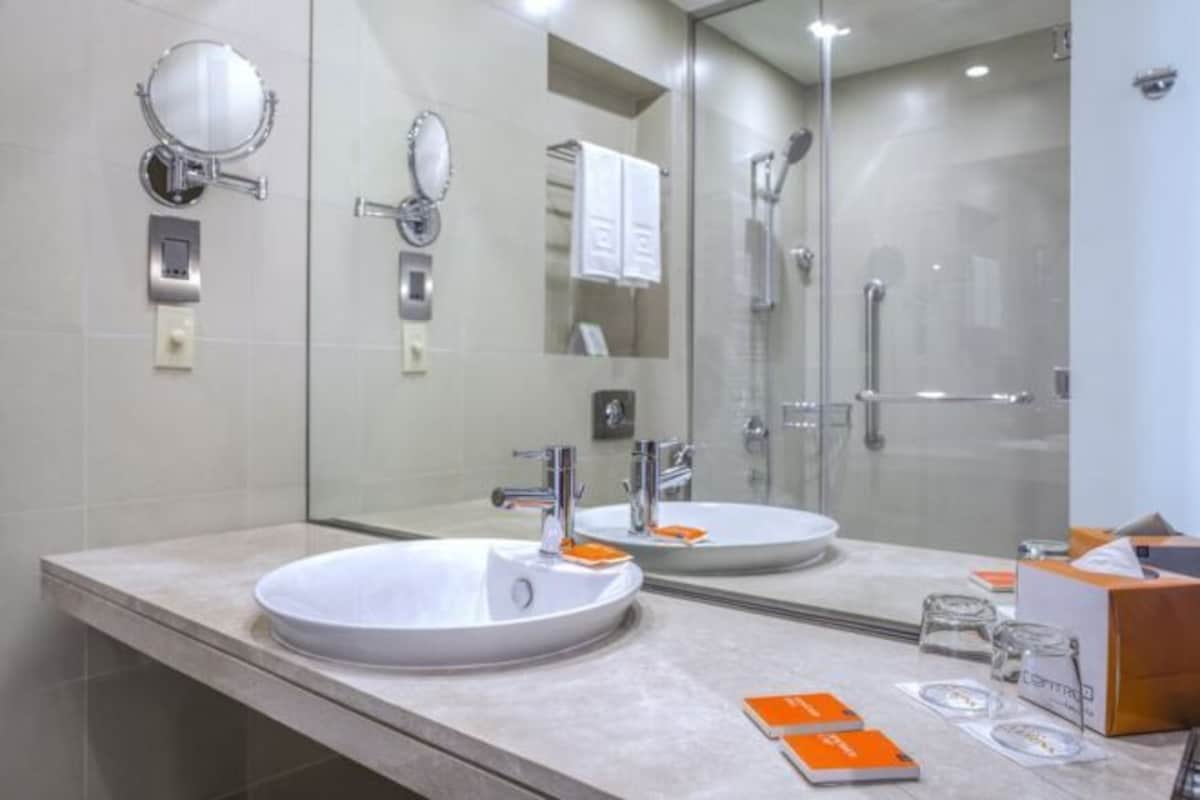 A modern bathroom with a large mirror, a sink, and a glass shower enclosure.