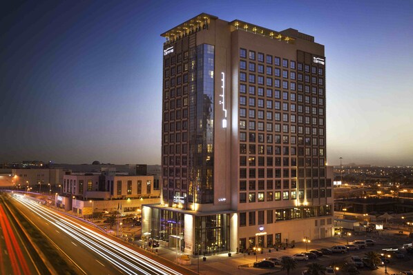 Un grand hôtel à plusieurs étages, doté de larges fenêtres et d’une façade bien éclairée.