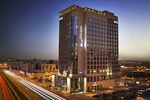 A high-rise hotel with multiple floors, large windows, and a well-lit facade.