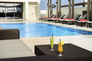 A pool area with lounge chairs and two drinks on a table.