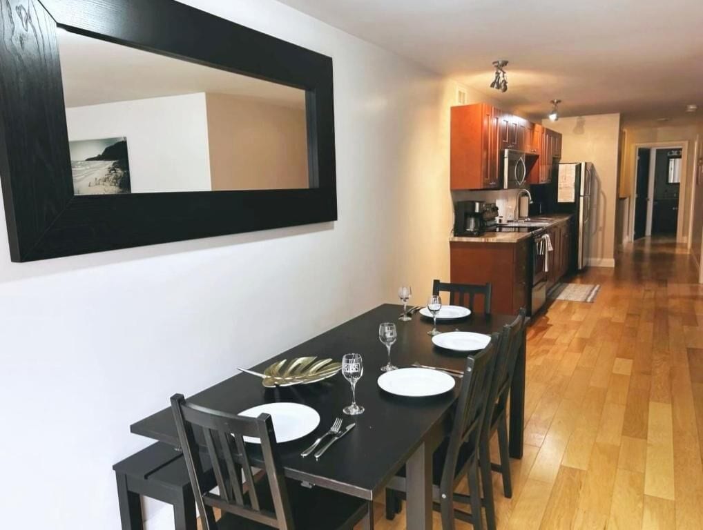 A dining area with a black table set for four, wooden chairs, and a large mirror on the wall.