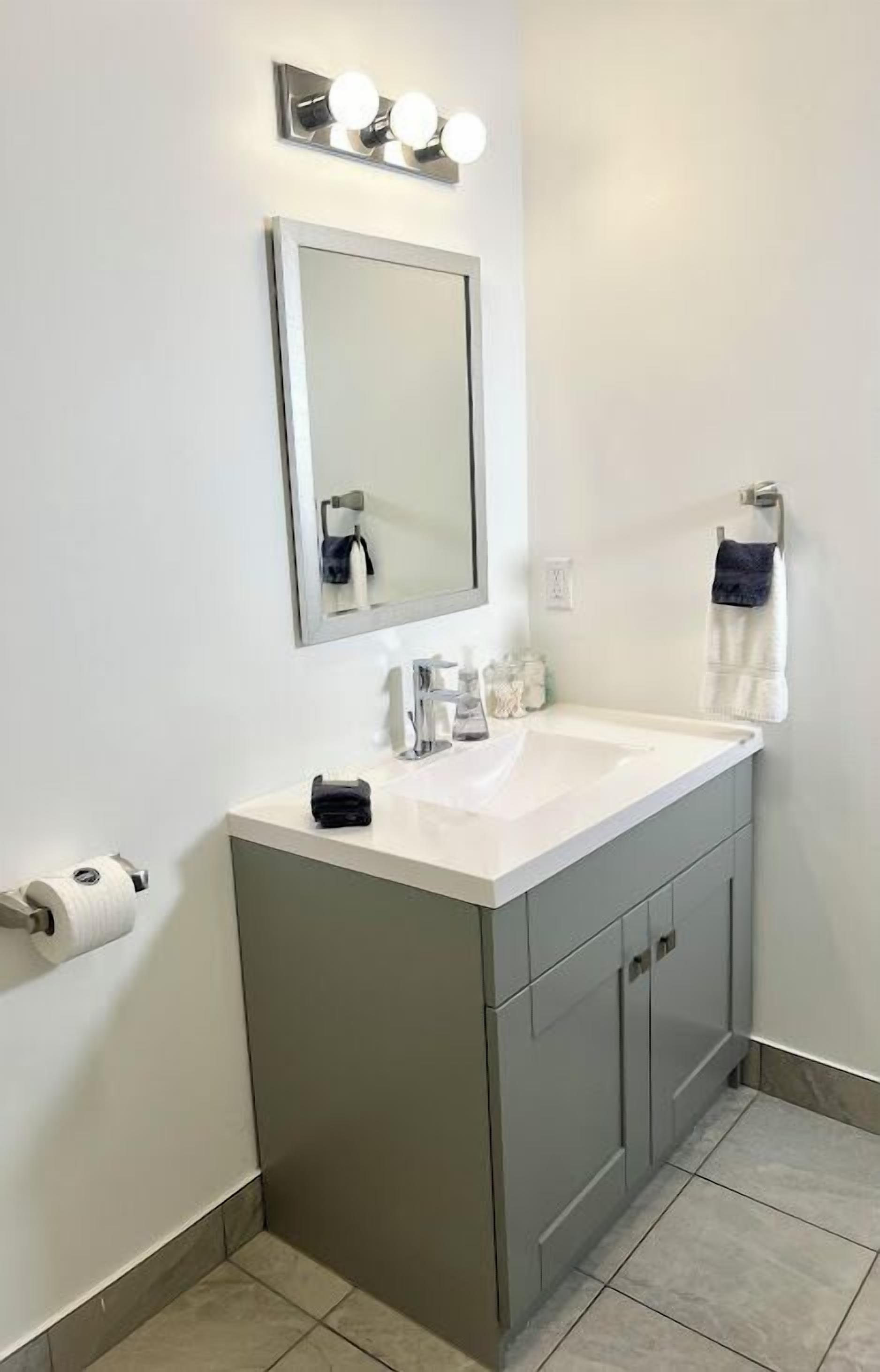 A bathroom with a white sink, a mirror, and a towel rack.