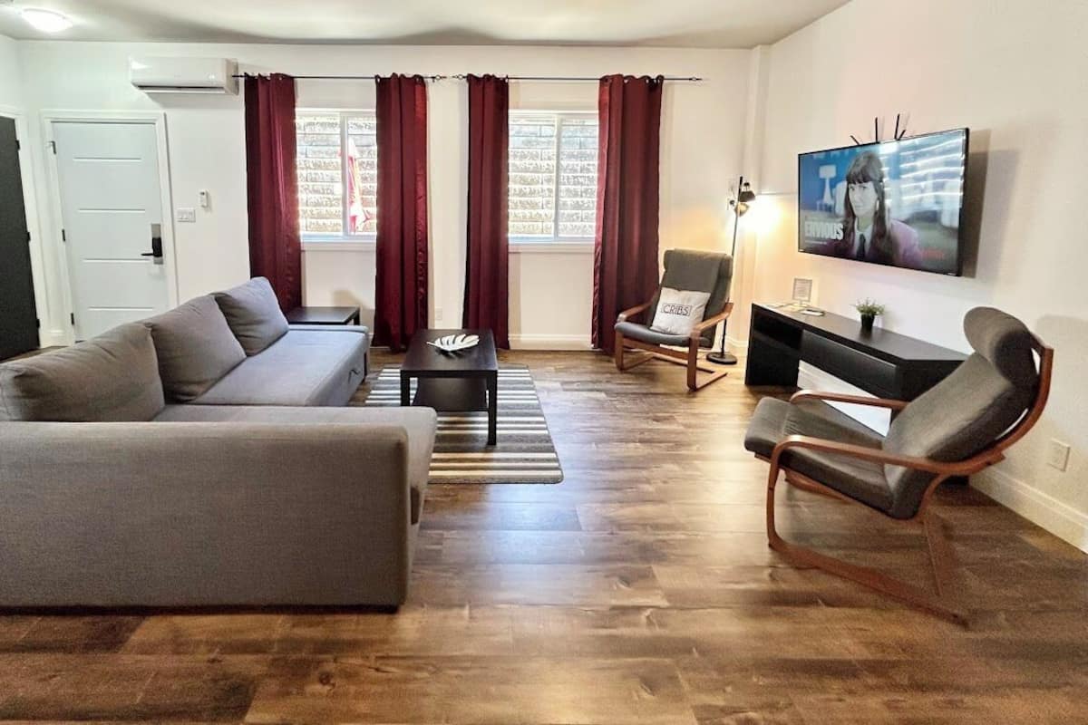 Ein Wohnzimmer mit Sofa, Sesseln, Couchtisch und Fernseher.