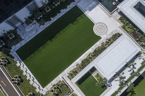 An aerial view of a landscaped courtyard with a central green lawn, surrounded by pathways and bordered by buildings with white walls and decorative elements. - Shangri-La Colombo (Colombo)