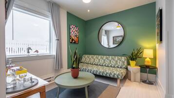 Una sala de estar con un sofá, una mesa redonda de centro, un espejo y una ventana con cortinas.