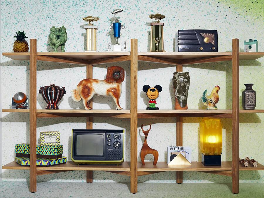 A wooden shelf unit with various decorative items including a pineapple, a frog figurine, a dog figurine, a Mickey Mouse head, and a rooster figurine.