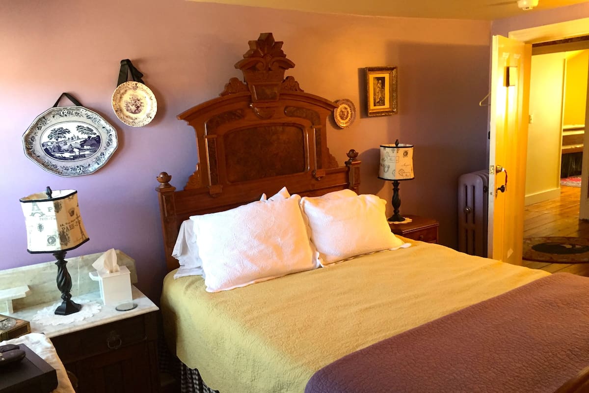A neatly made bed with a wooden headboard, a bedside table with a lamp, and a wall-mounted plate.