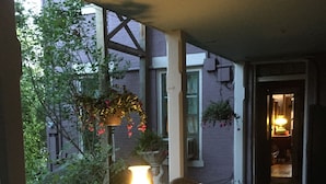 A cozy outdoor seating area with wicker furniture and a table with a lit lamp. - Annie Wiggins Guest House (Galena)
