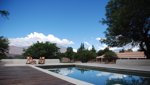 A swimming pool with a wooden deck, two lounge chairs, and a mountainous backdrop. - La Vaca Tranquila (San Carlos)