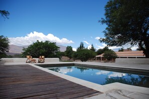A swimming pool with a wooden deck, two lounge chairs, and a mountainous backdrop. - La Vaca Tranquila (San Carlos)