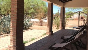 A covered patio area with brick pillars, a tiled floor, and a lounge chair. - La Vaca Tranquila (San Carlos)