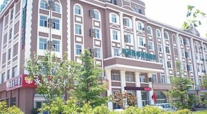 Hotel de diverses plantes amb entrada central, envoltat de vegetació.