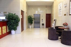 Rebuda d'hotel amb taulell de recepció, plantes en testos, ascensor i zones d'estar.