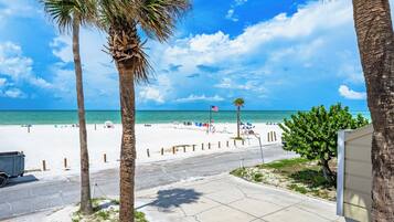 Blick auf einen Strand mit Palmen, einer Flagge und blauem Himmel.