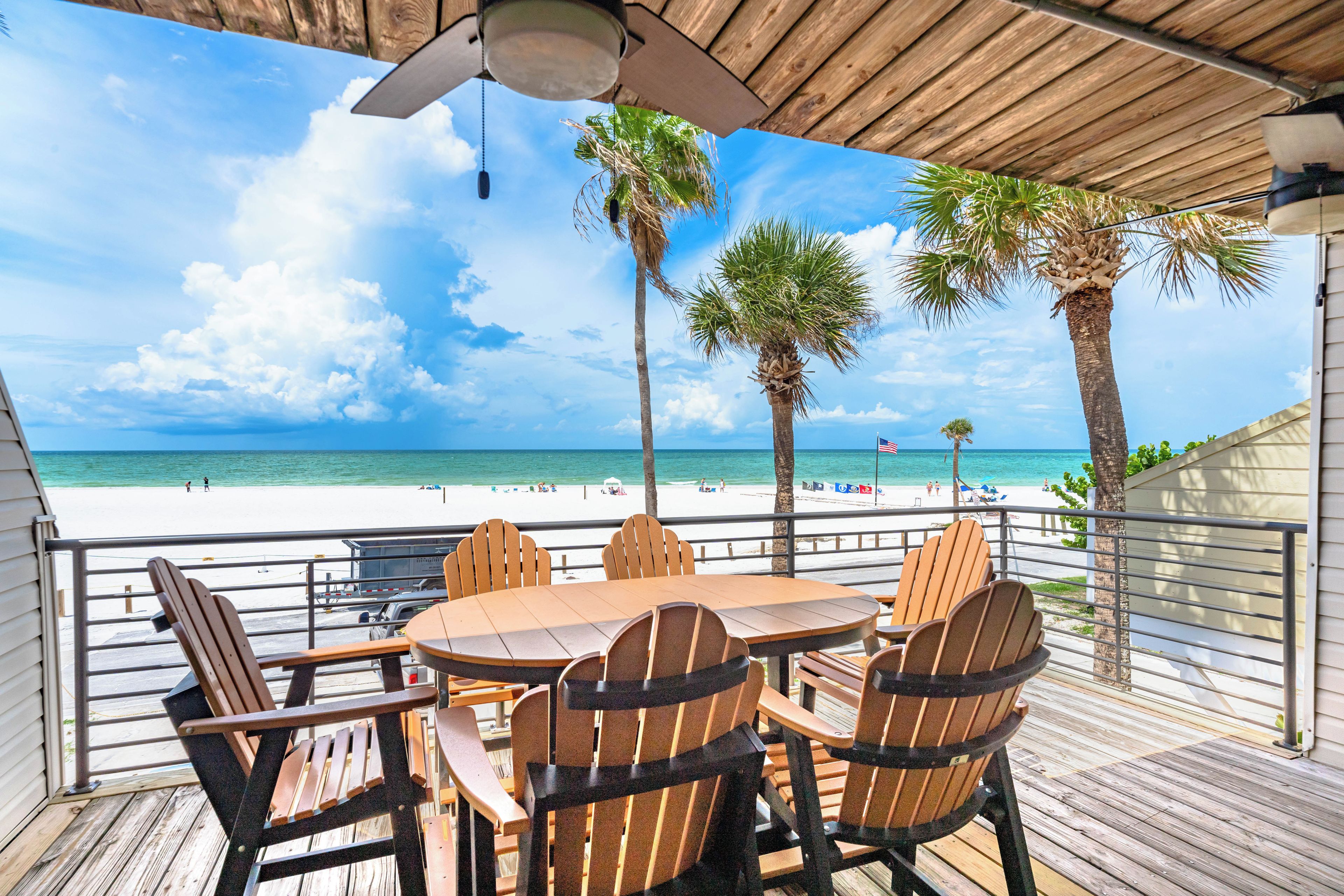 A wooden deck with a table and chairs overlooking a beach.