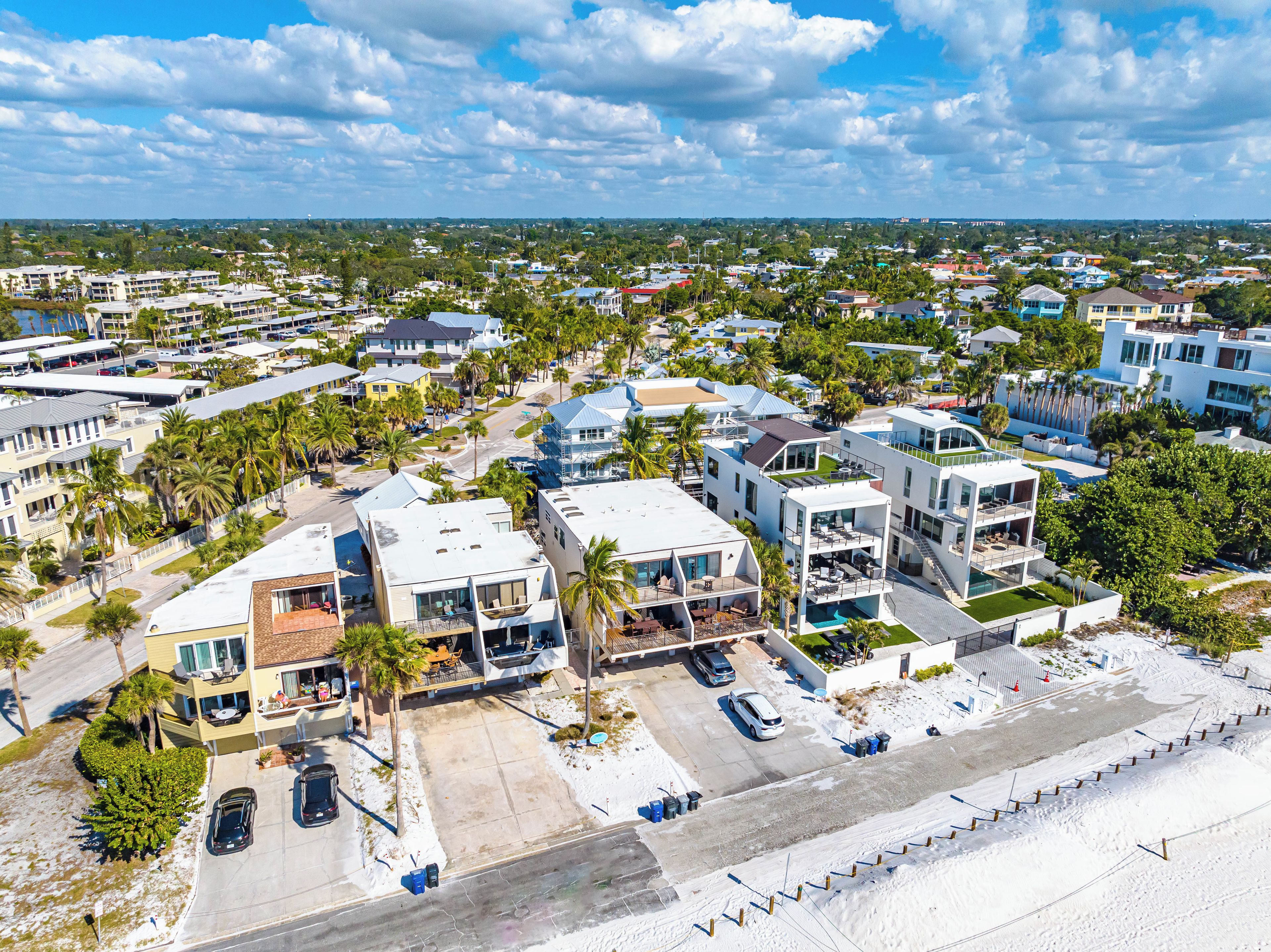 A coastal residential area with modern houses, a swimming pool, and a beach in the foreground.