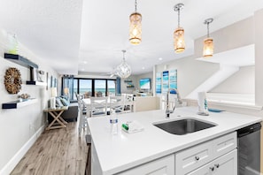 A modern kitchen with a large island, white cabinetry, and pendant lighting. - Fanta-Sea on the Beach by Beachside Management - 49 Beach Rd (Siesta Key)