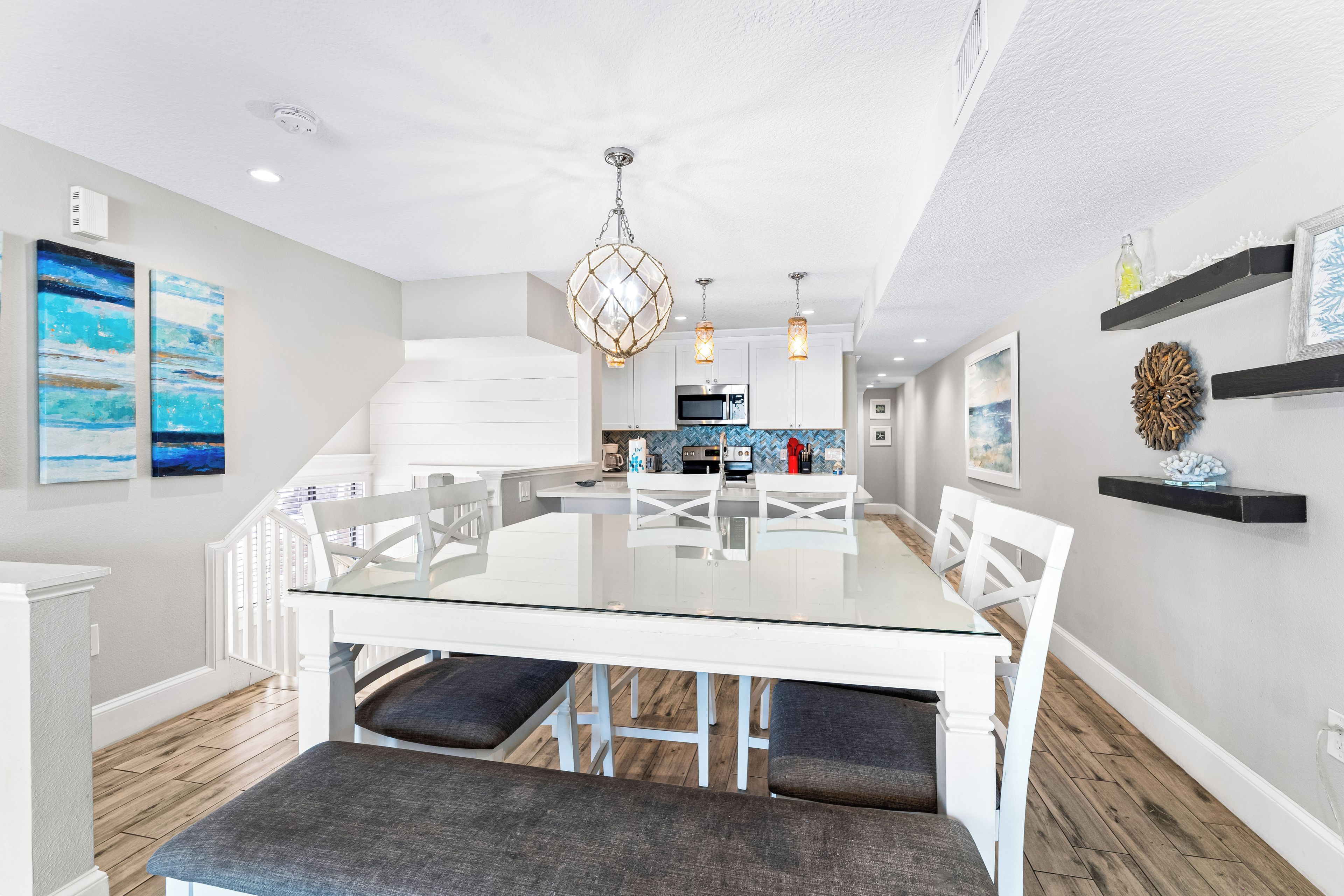 A modern kitchen with white cabinetry, a central island, and pendant lighting.
