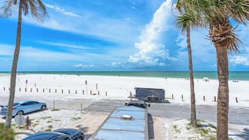 Vista de una playa con un estacionamiento, una caravana y palmeras.