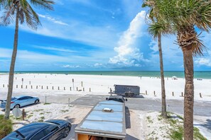 A beach view with a parking area, a trailer, and palm trees. - Fanta-Sea on the Beach by Beachside Management - 49 Beach Rd (Siesta Key)