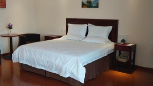 A neatly made bed with white linens, a wooden headboard, and two bedside tables with lamps.