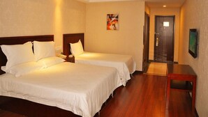 A hotel room with two beds, wooden flooring, a painting on the wall, and a door leading to another room. - GreenTree Inn Taizhou Taixing East Guoqing Road RT Mart Business Hotel (Taizhou)