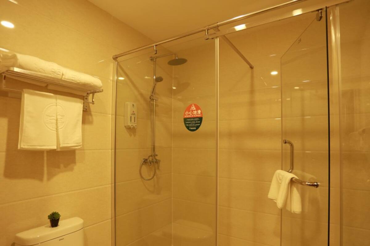 A glass-enclosed shower area with a toilet and a towel rack.