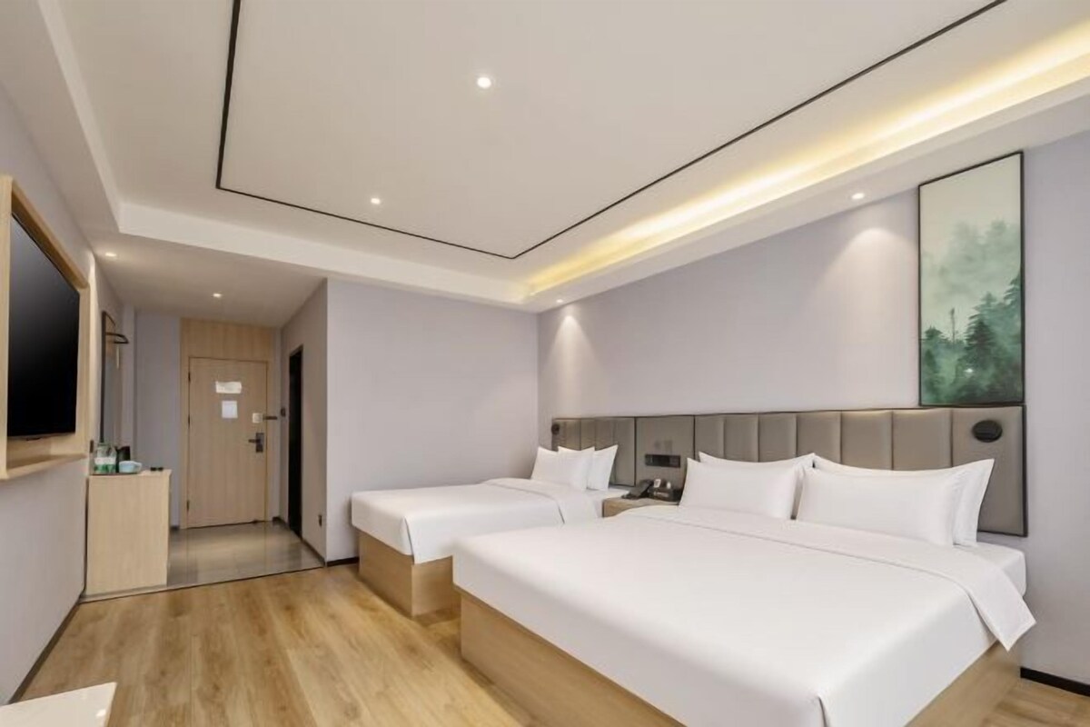 A hotel room with two beds, a desk, a mirror, and a painting on the wall.