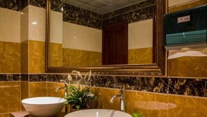 Une salle de bain avec deux lavabos, un miroir et une bouteille verte posée sur le comptoir.