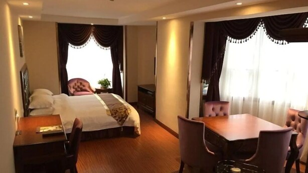 Une chambre d’hôtel comprenant un grand lit, un bureau, une chaise, une table à manger avec des chaises et un téléviseur.