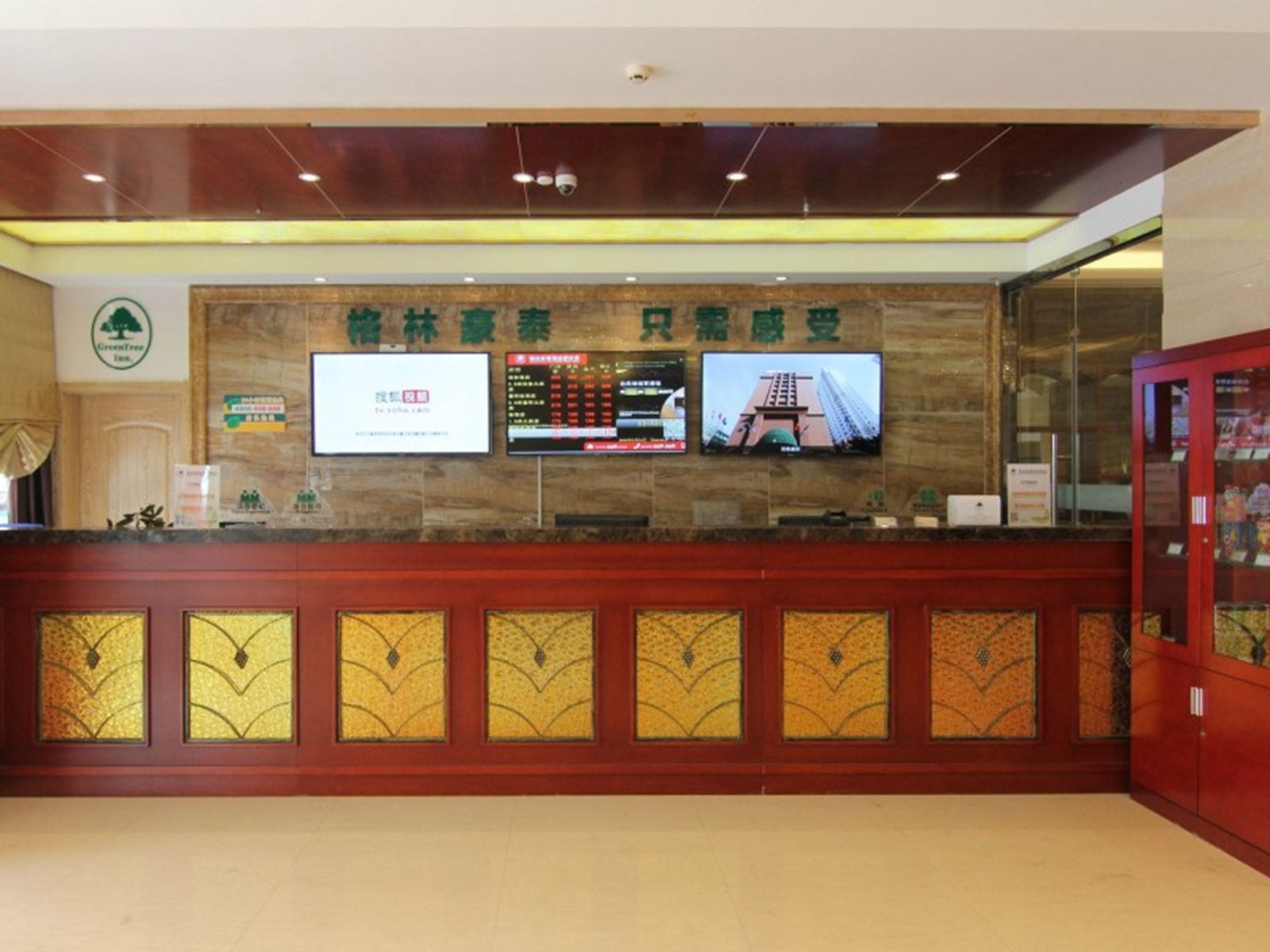 A reception desk with a digital display, a sign with Chinese characters, and a glass display case.