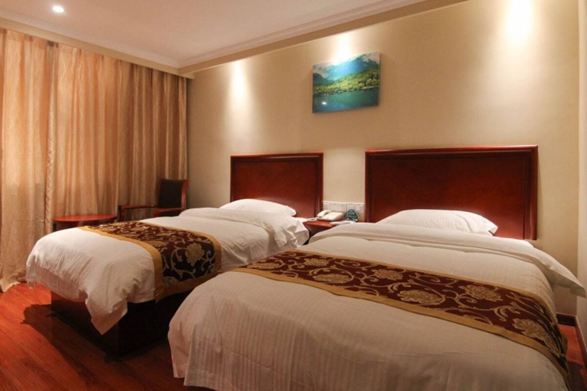 A hotel room with two beds, a painting on the wall, and a wooden floor.