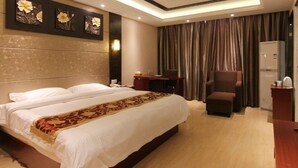 A hotel room with a large bed, a desk, a chair, and a minibar. - GreenTree Inn JiangSu ZHenjiang Jurong Yalong Hotel (Zhenjiang)