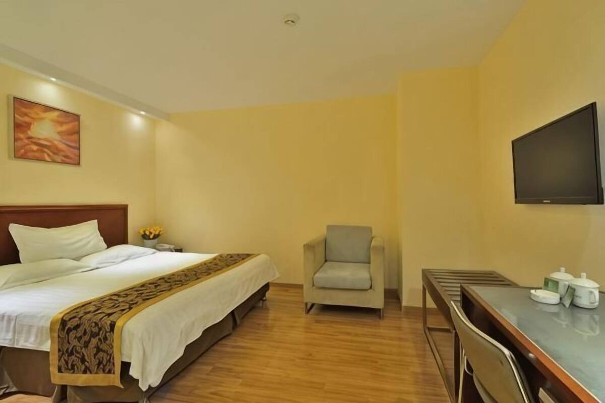 Una habitación de hotel con una cama, una silla, un escritorio y un televisor.