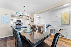 A modern kitchen with white cabinetry, a stainless steel microwave, and a hanging light fixture. - Fanta-Sea on the Beach by Beachside Management - 55 Beach Rd (Siesta Key)