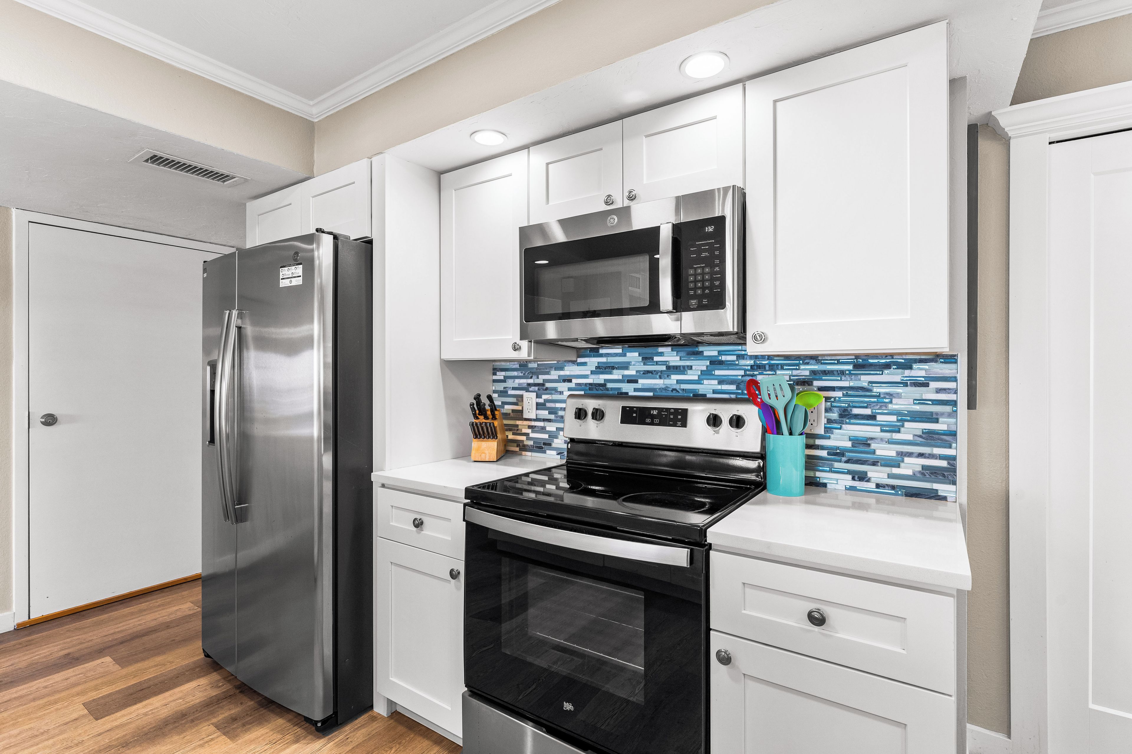 Una cocina moderna con electrodomésticos de acero inoxidable, armarios blancos y salpicadero de azulejos.