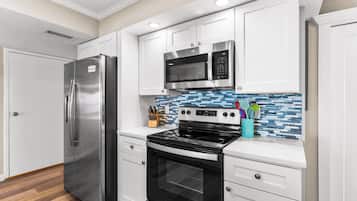 Una cocina moderna con electrodomésticos de acero inoxidable, armarios blancos y salpicadero de azulejos.