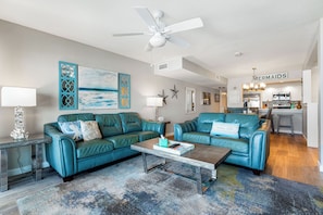 A living room with two teal leather sofas, a coffee table, and a ceiling fan. - Fanta-Sea on the Beach by Beachside Management - 55 Beach Rd (Siesta Key)