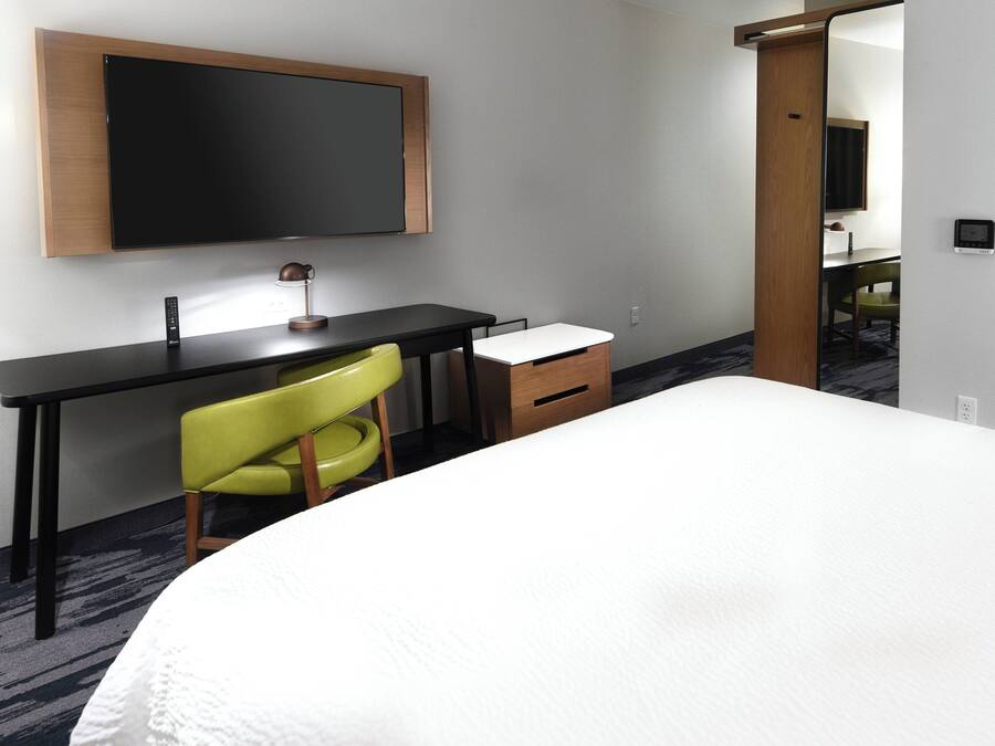 Ein Hotelzimmer mit einem Bett, einem Schreibtisch, einem Stuhl, einem Flachbildfernseher und einem kleinen Schrank.